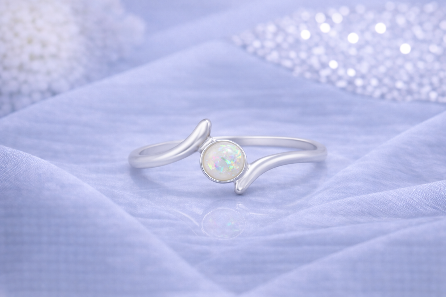 Ring Essence silber mit hellem Zierstein auf blauem Tuch